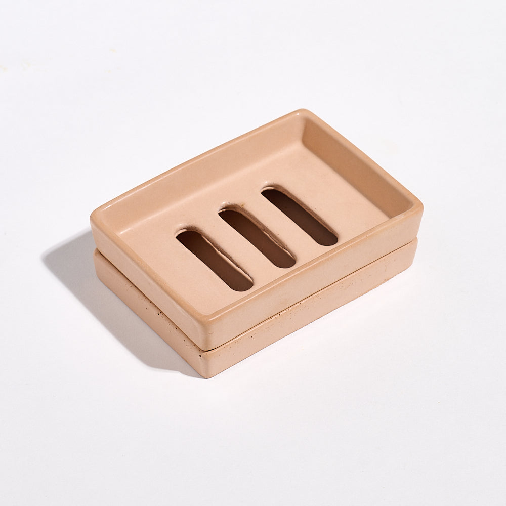 Terracotta soap dish with three drainage holes with a tray on a light gray background