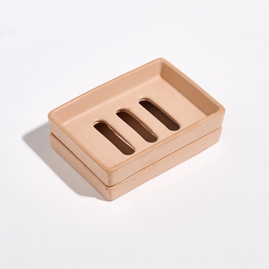 Terracotta soap dish with three drainage holes with a tray on a light gray background