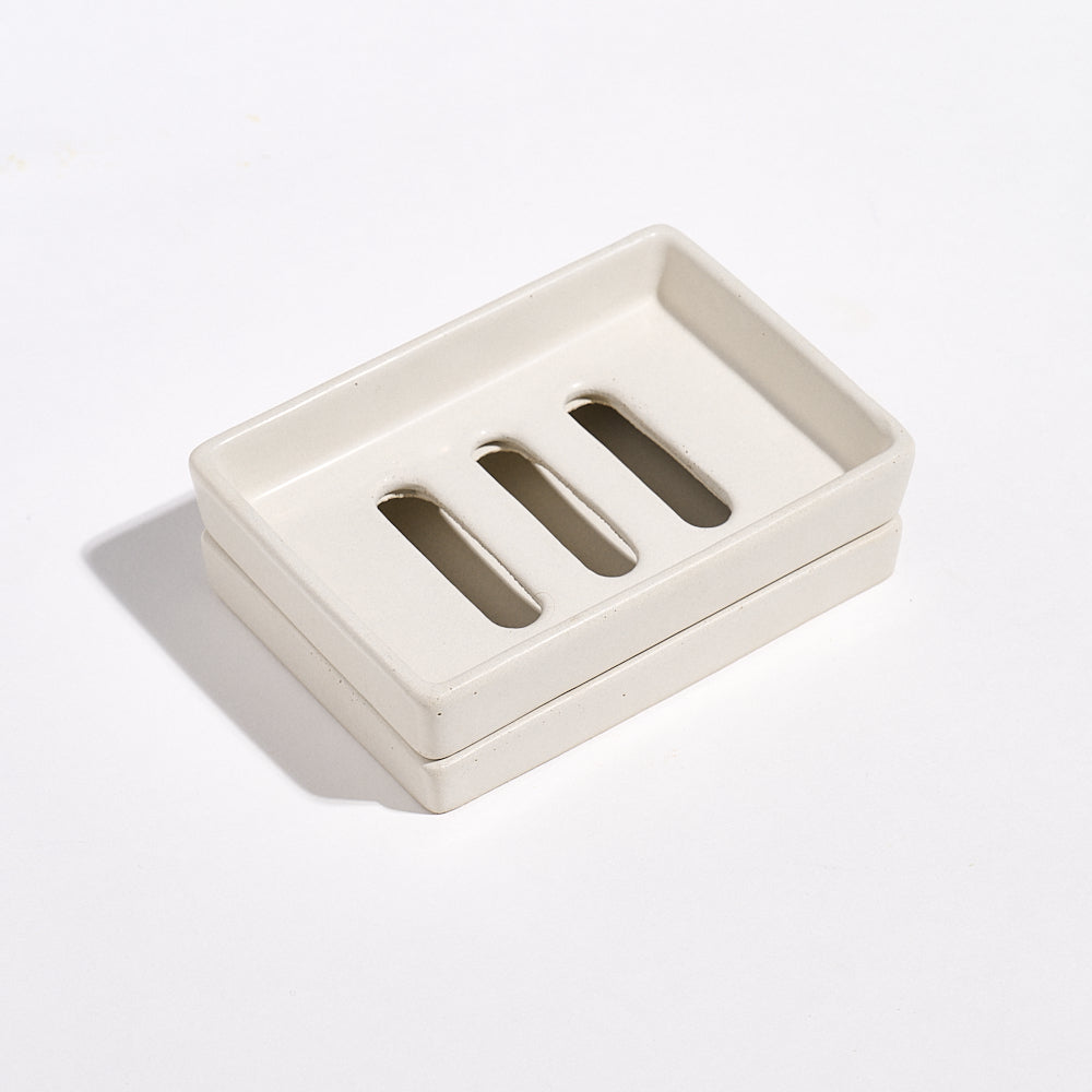 Portland Stone-coloured Jesmonite soap dish with three slots and a tray on a light gray background.
