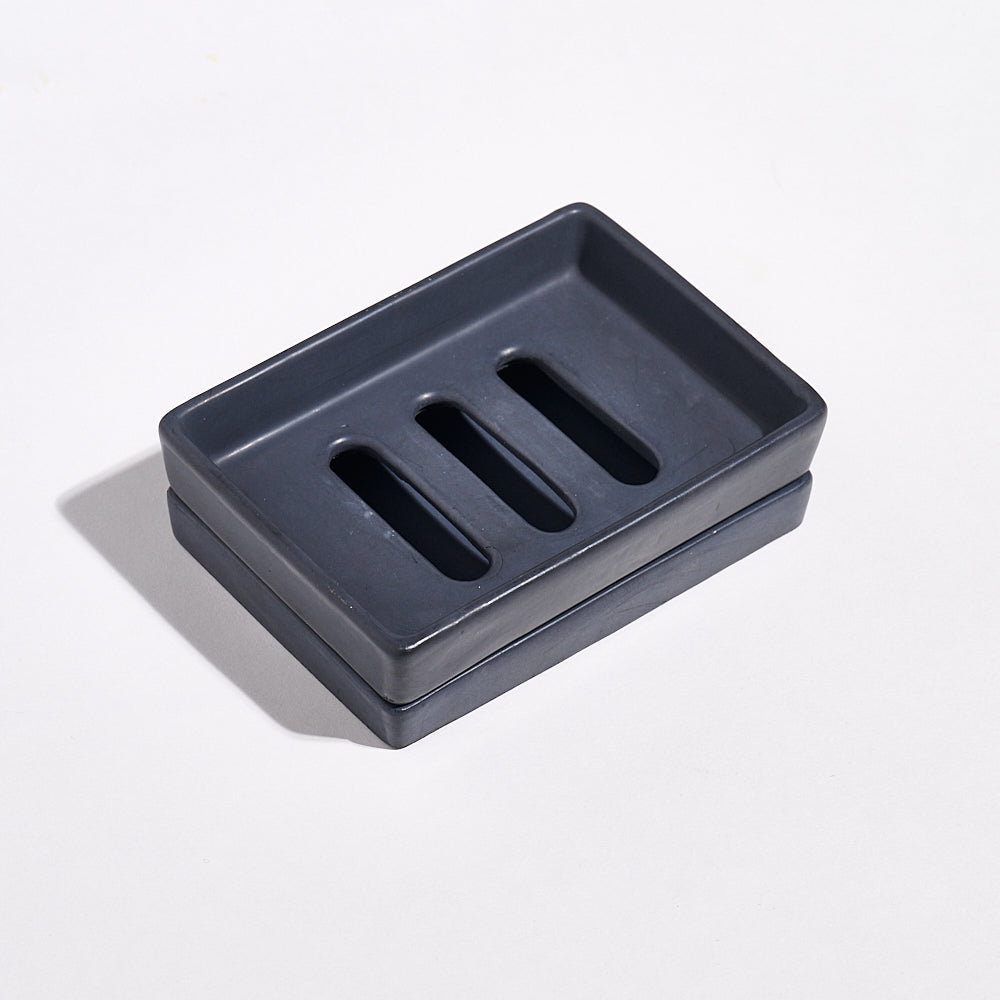 Charcoal black Jesmonite soap dish with three slots and a tray on a light gray background