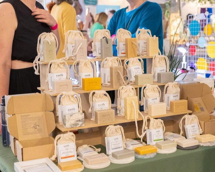 Two women standing behind a table displaying various products at an event.