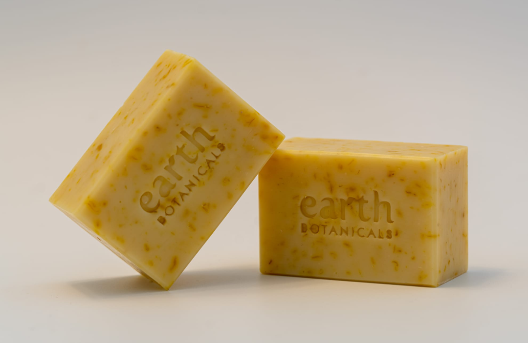 Two bars of yellow soap with 'earth botanicals' branding on a light background