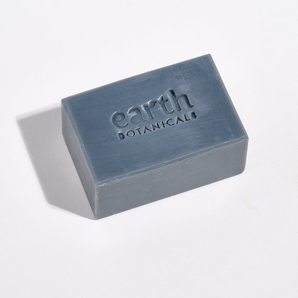 Bar of soap with 'earth botanicals' branding on a light gray background
